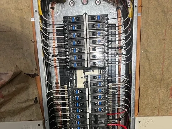Open commercial panelboard with full breaker rows, a surge protector, and organized conductor runs in a framed wall.