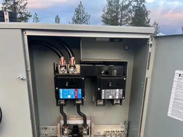 An open Eaton service enclosure at dusk showing main breakers, feeder lugs, and a neutral bar.