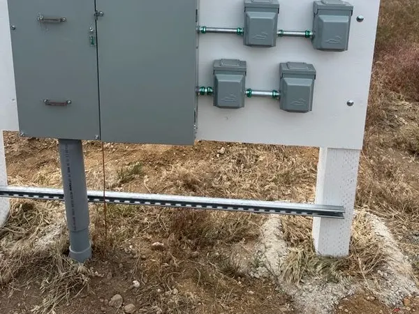 A meter enclosure and weatherproof boxes joined by conduit on a field-mounted service board.