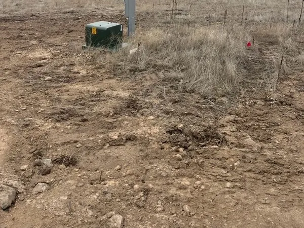 A utility transformer pedestal and meter pedestal set in an open rural lot.