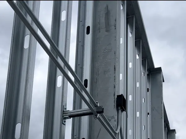 Precise EMT conduit offset bends run up steel-stud framing on a commercial high-rise, with a Silicon Valley campus skyline below.