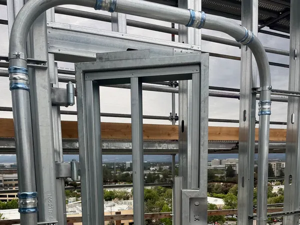 Galvanized conduit racks and structural steel on a commercial job, framed against the sky.