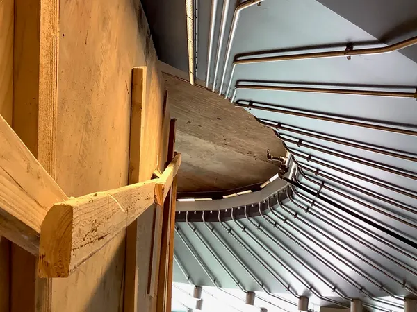A sweeping curved bank of parallel EMT conduits follows a commercial entrance canopy alongside linear LED lighting.