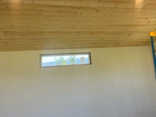 Two lit recessed can lights in a tongue-and-groove wood ceiling above a mountain-view window.