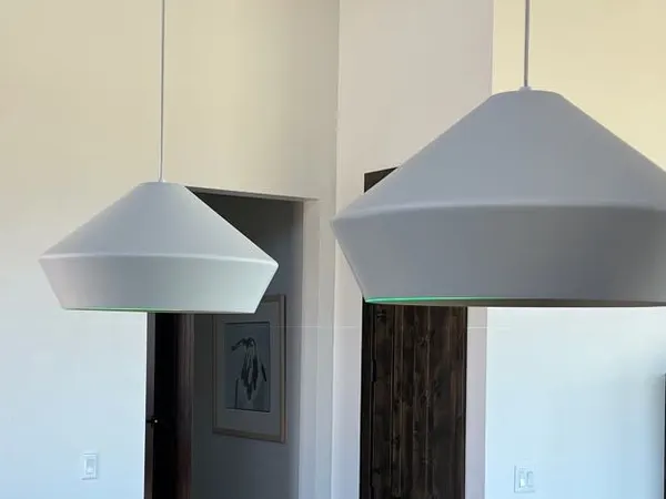 Two large white pendant lights hanging over a kitchen island in a finished home.