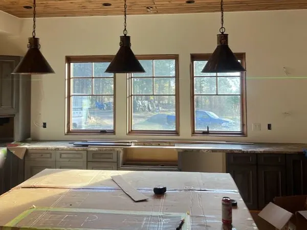 Three matching pendants hung over a remodeled kitchen island beneath new windows.
