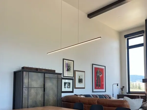 A long linear pendant over a modern living room with mountain views through the windows.