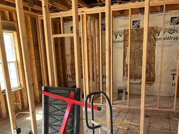 Residential framing rough-in with yellow NM cable run to boxes over house-wrap sheathing.