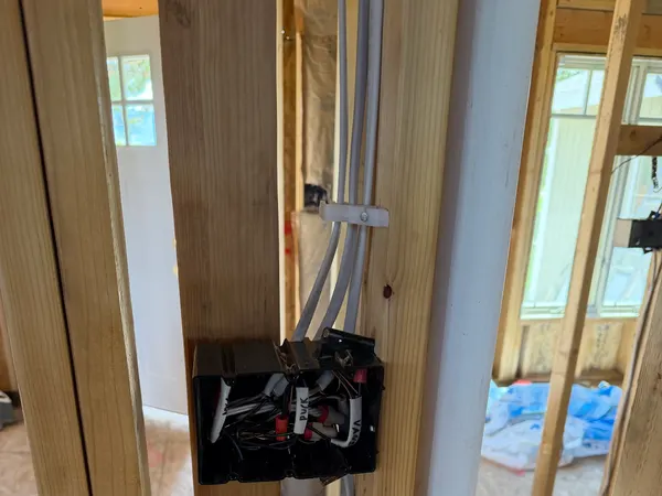A multi-gang rough-in device box with wired connectors on framing in a home under construction.