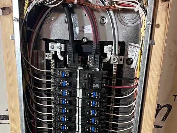 An open breaker panel with dense, neatly dressed white circuit wiring in a framed wall.