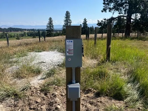 An Eaton meter and disconnect enclosure on a wood post with conduit riser in an open field.