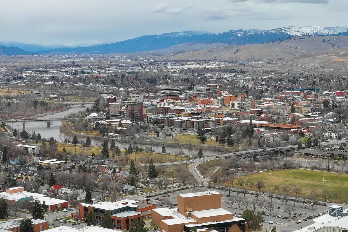 Downtown Missoula, Montana seen from above, with the Clark Fork River running through the city and the Rattlesnake hills beyond.